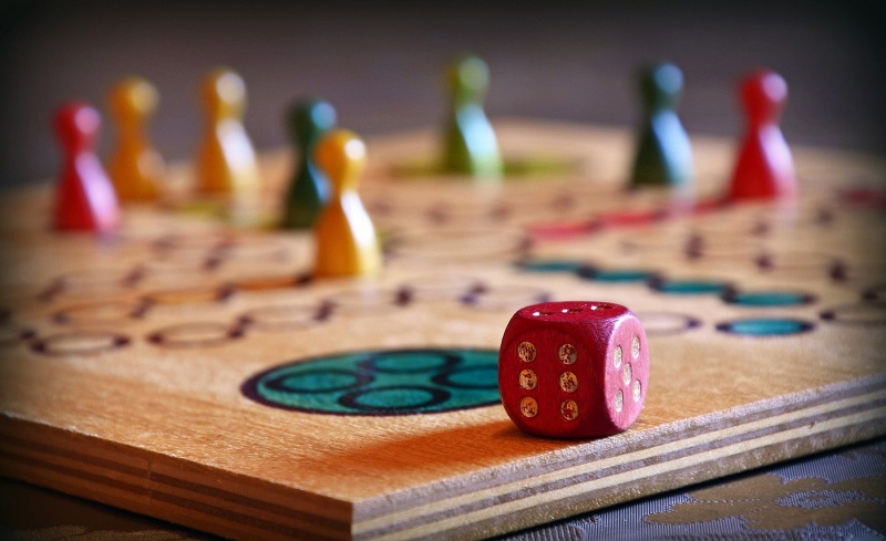 Pions et dé sur un plateau de jeu en bois