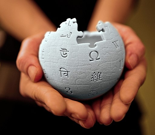 Mains tenant une figurine du logo Wikipedia