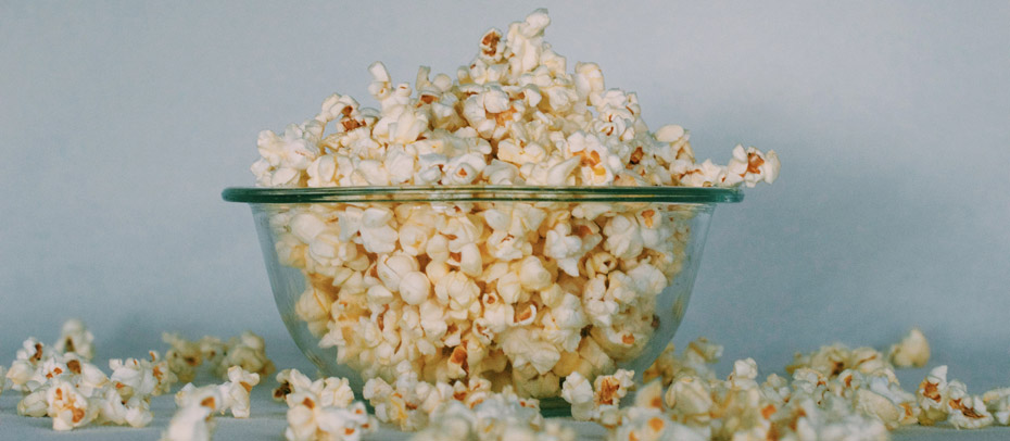 un saladier en verre rempli de pop-corn (ça déborde également).