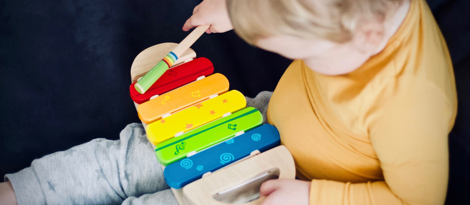 Un jeune enfant (18 mois) tenant un xylophone et une baguette