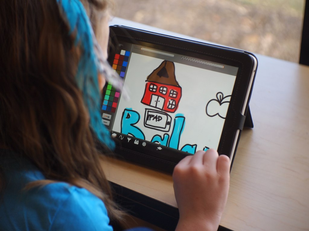 Plan serré sur une enfant dessinant sur une tablette
