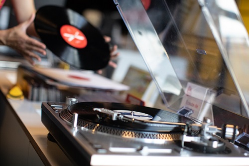 Main posant un vinyle sur une platine de la Galerie