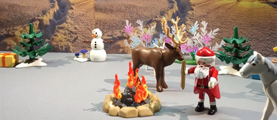 Extrait du film en stop motion : le décor est une rue pavée à l'époque des fêtes. Une boîte aux lettres, un sapin et un playmobil avec un sac.