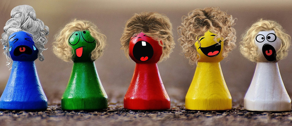 Cinq pions de jeu de société (bleu, vert, rouge, jaune et blanc)avec des perruques et une expression différente peinte : joie, tristesse, colère...