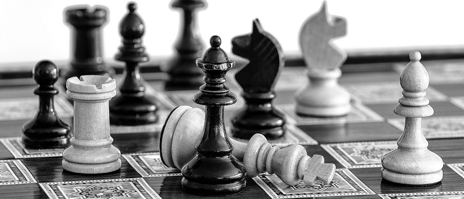 Un plateau d'échecs en noir et blanc avec des pions debout, d'autres tombés.