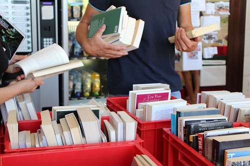 mains fouillant dans des caisses rouges remplies de livres