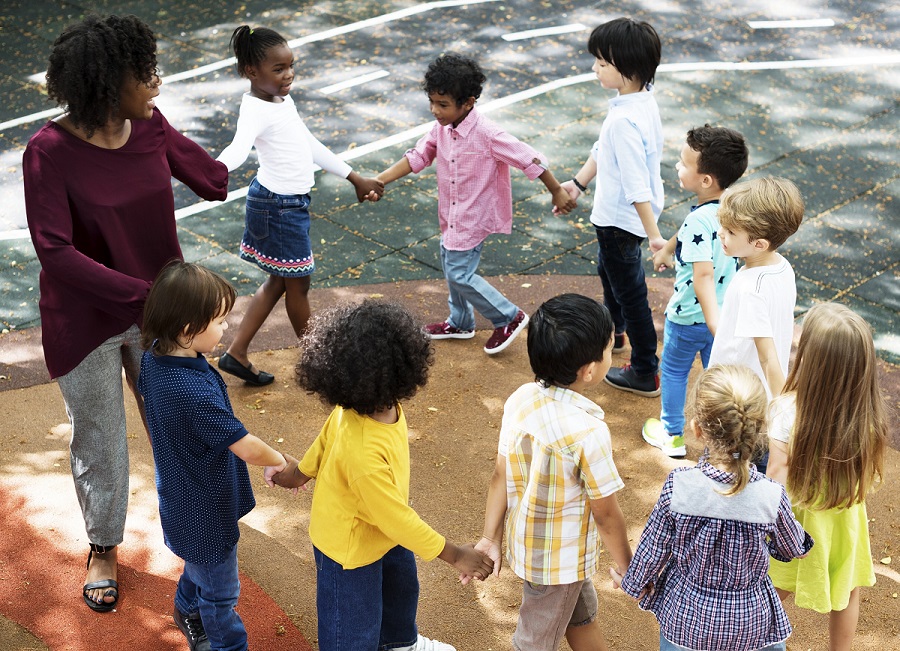 Ronde de petits enfants dans la cour de l'école avec leur institutrice