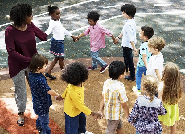 ronde d'enfants avec leur institutrice dans la cour de l'école