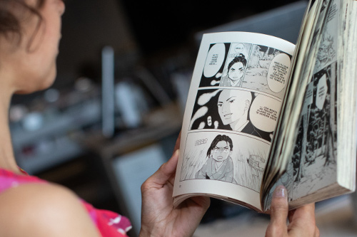 personne vue de dos tenant un manga ouvert
