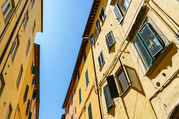 ruelle très ensoleillée avec deux façades jaunes d'immeubles aux volets fermés