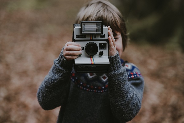 enfant tenant polaroid dans un paysage d'automne