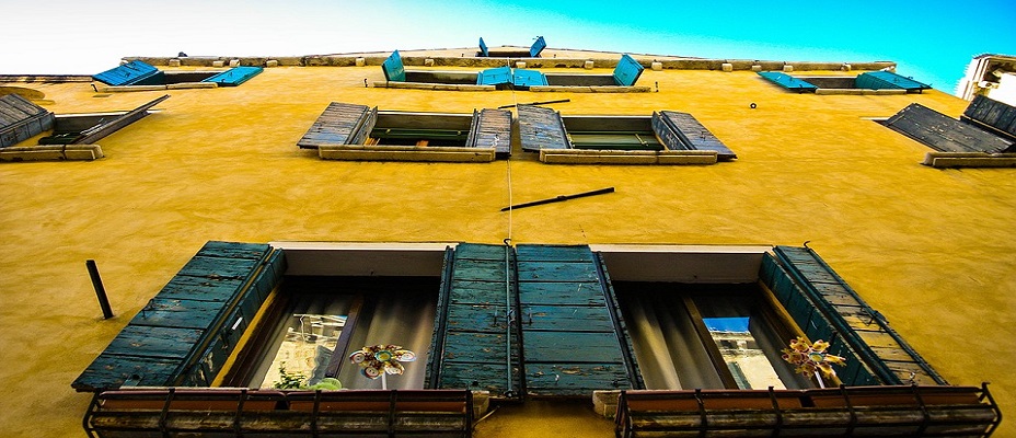 façade jaune d'un immeuble ancien avec volets verts