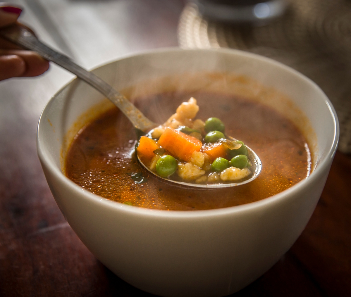 Gros plan sur une soupe dans un bol avec une cuillière qui contient plusieurs légumes