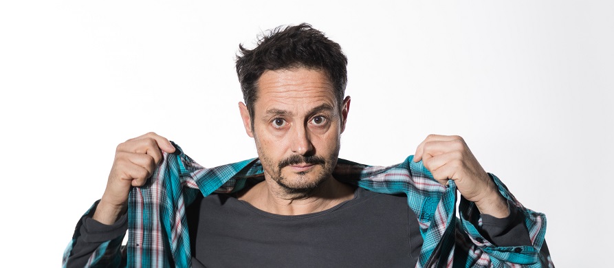 Nicolas Richard debout ouvrant sa chemise à carreaux