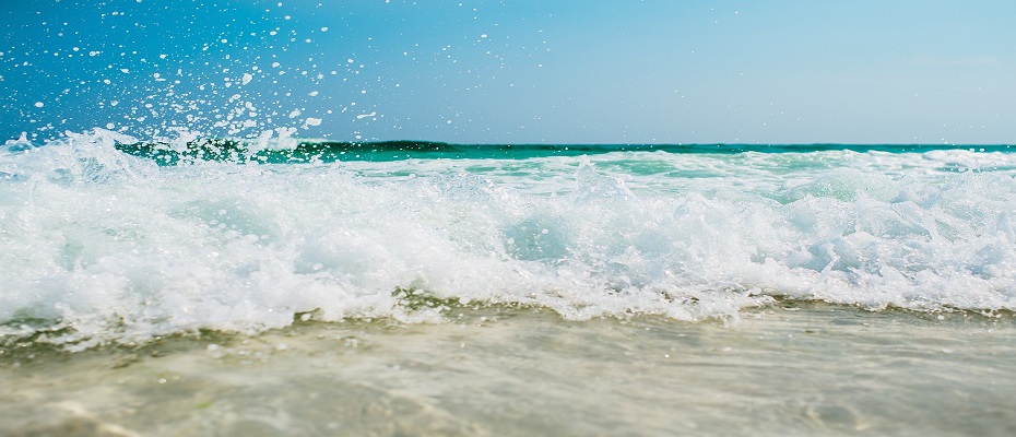grosse vague d'écume s'échouant sur le sable blanc avec un ciel lumineux et paradisiaque