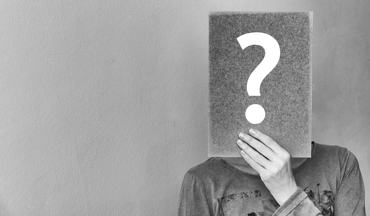 personne tenant un livre devant son visage où apparait un point d'interrogation