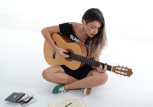 femme jouant de la guitare devant un livre ouvert 