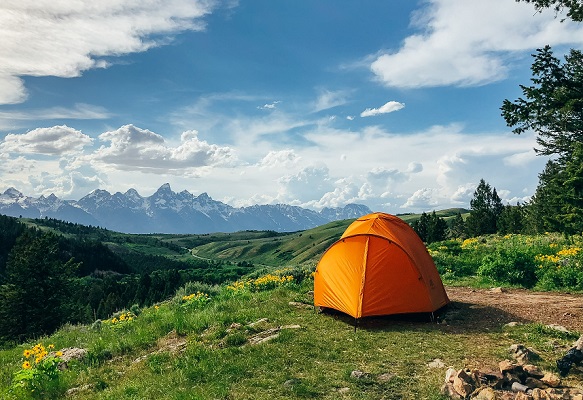 toile de tente orange en plein air au milieu d'un paysage de montagne l'été