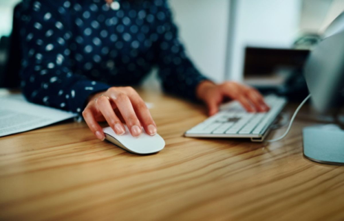 torse et mains d'une personne avec la main droite sur une souris d'ordinateur et la gauche sur un clavier