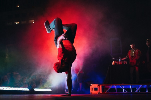 danseur de break dance tenant sur une main sur une scène aux lumières rouges