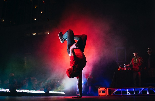 danseur de break dance tenant sur une main sur une scène aux lumières rouges