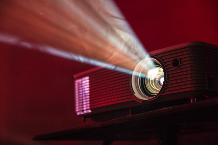 rétroprojecteur avec faisceau de lumière sur fond rouge bordeaux.