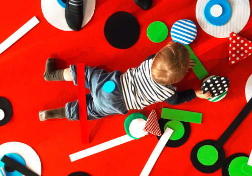 Enfant allongé sur un tapis avec motifs de couleurs