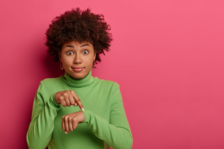 jeune femme métisse pointant son poignet avec son index