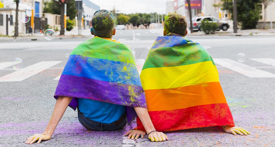 Deux personnes assis portant un drapeau coloré 