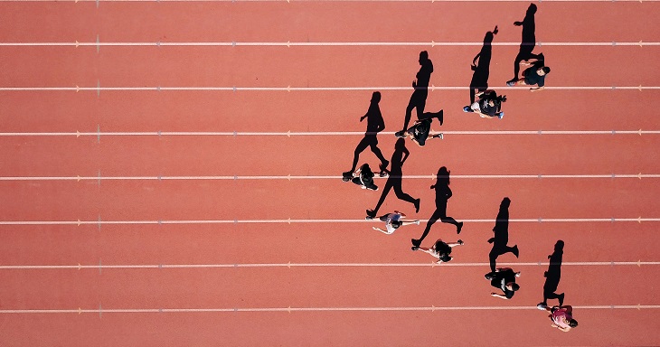 piste d'athlétisme avec des coureurs en prise de vue aérienne formants une flèche