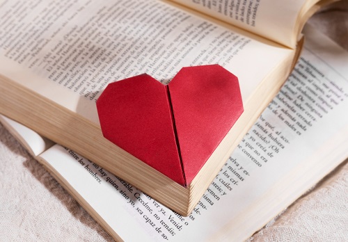 papier plié en forme de coeur posé sur un livre