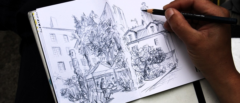 un main tient un crayon sur un carnet de croquis 