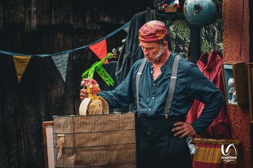 Un comédien sur scène sort une marionnette-poule d'une boîte remplie de foin