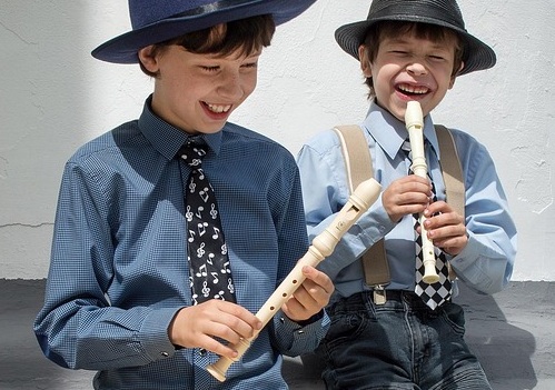 enfant riant et jouant de la flute à bec