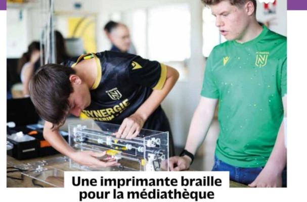 Un jeune penché sur l'embosseuse et un autre debout à droite