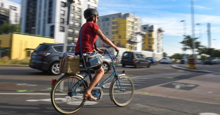 Une femme roulant sur un vélo dans le quartier de Pont-Rousseau (Rezé). A l'arrière, circulation automobile.