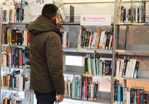Un homme devant l'étagère des réservations de la médiathèque