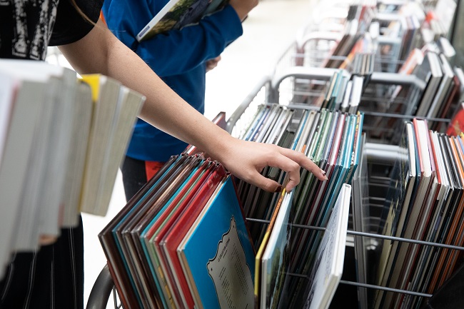 Une personne jeune cherchant des bandes dessinées dans un bac.